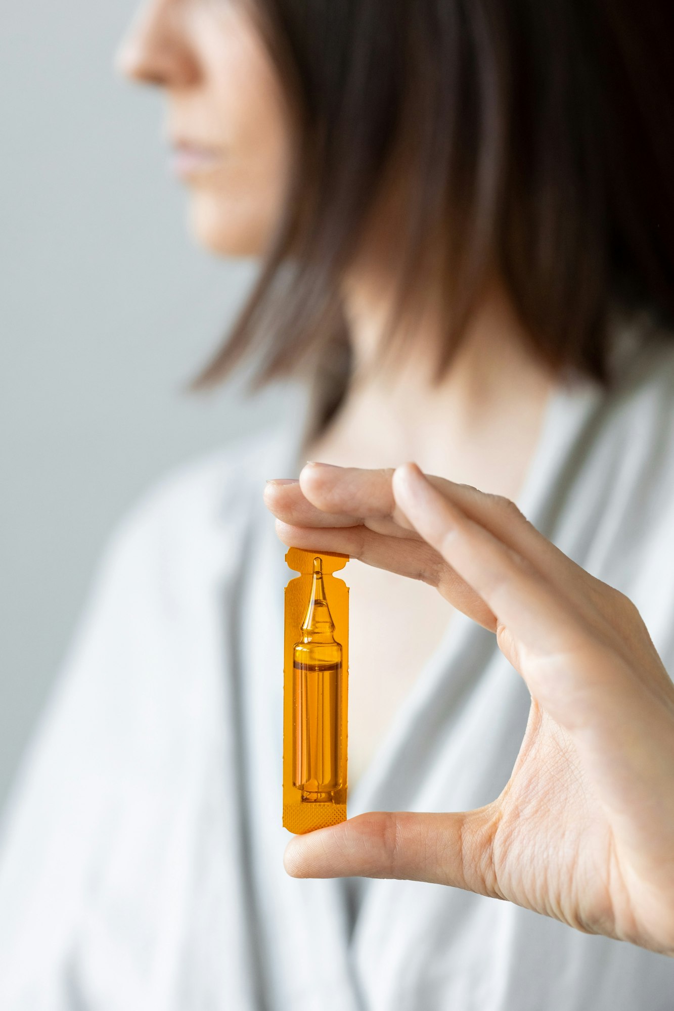 Caucasian woman holding an ampoule of vitamins for hair or skin, aminexil, hair restoration