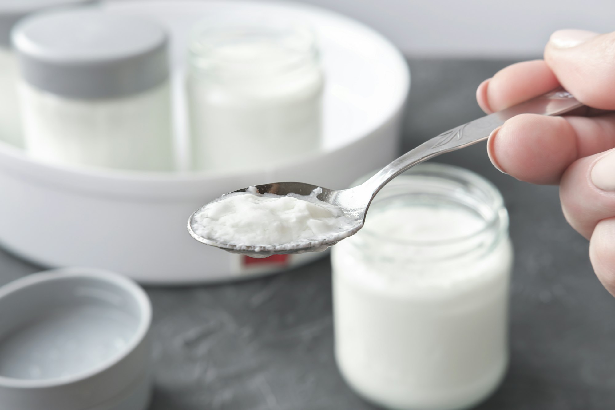 female hand holding a spoon with kefir or yogurt